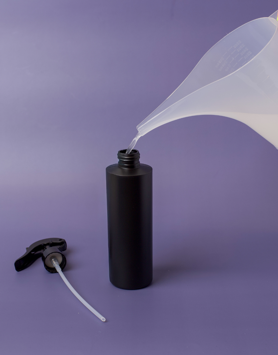 Pouring room spray into a bottle from a funnel pouring pitcher.